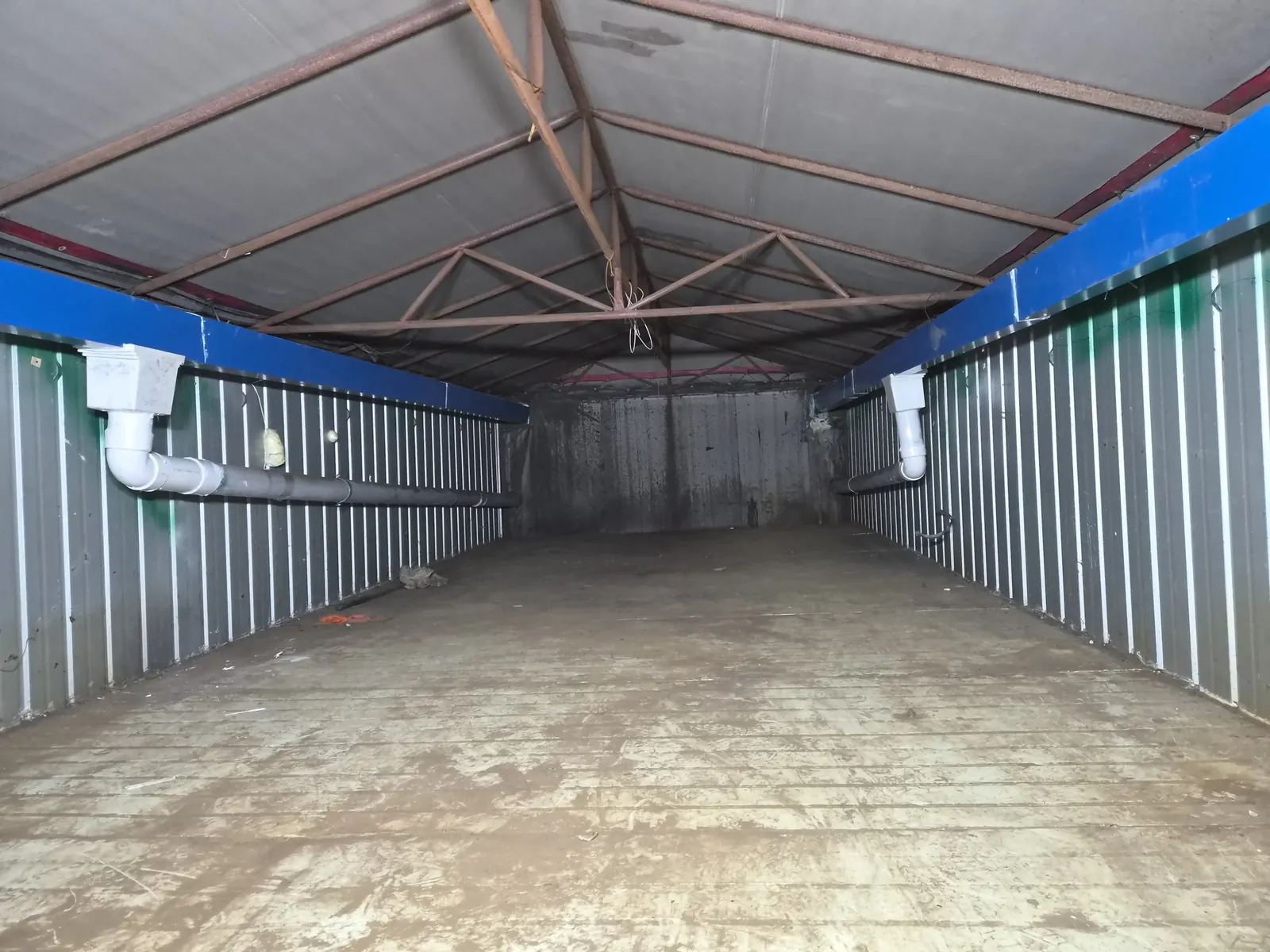 공장 내부 양쪽 벽면에 연결된 흰색 배수 PVC 파이프